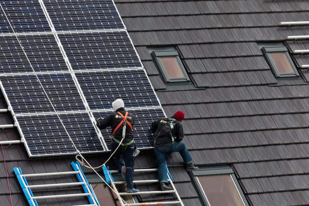Construction workers installing solar panels on a roof